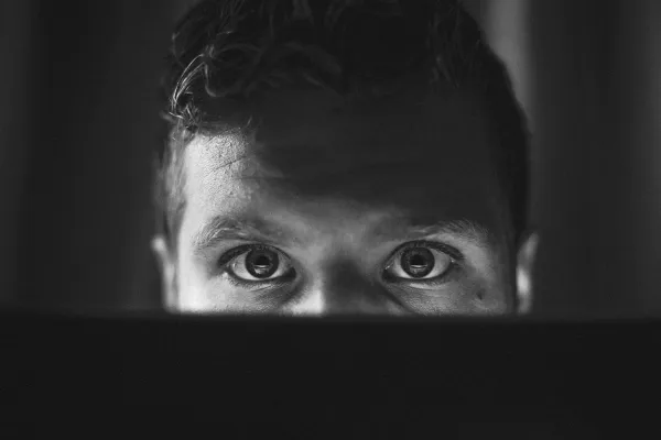 A man watching intently above their computer screen.